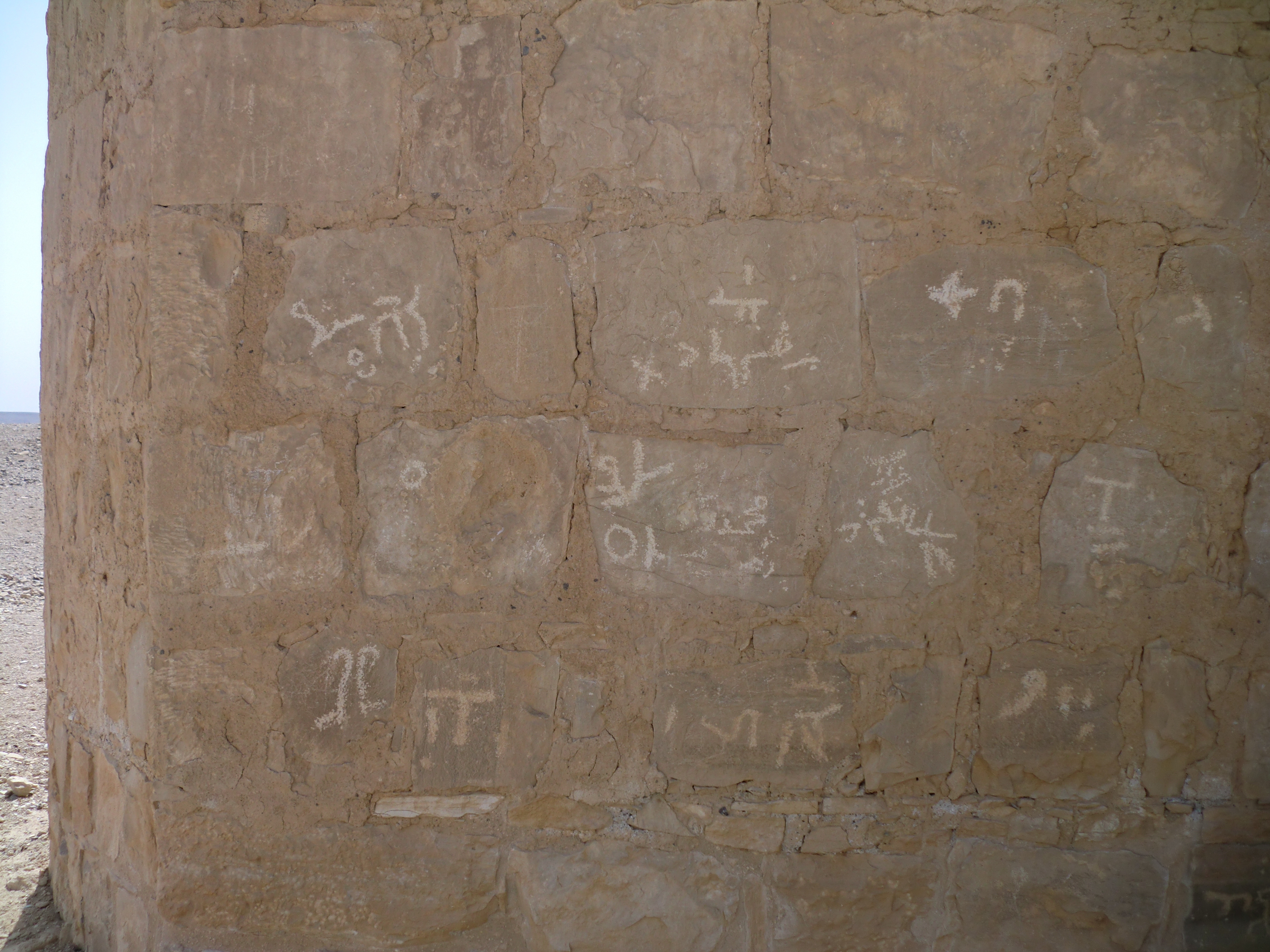 Stone wall with markings drawn on it in white.