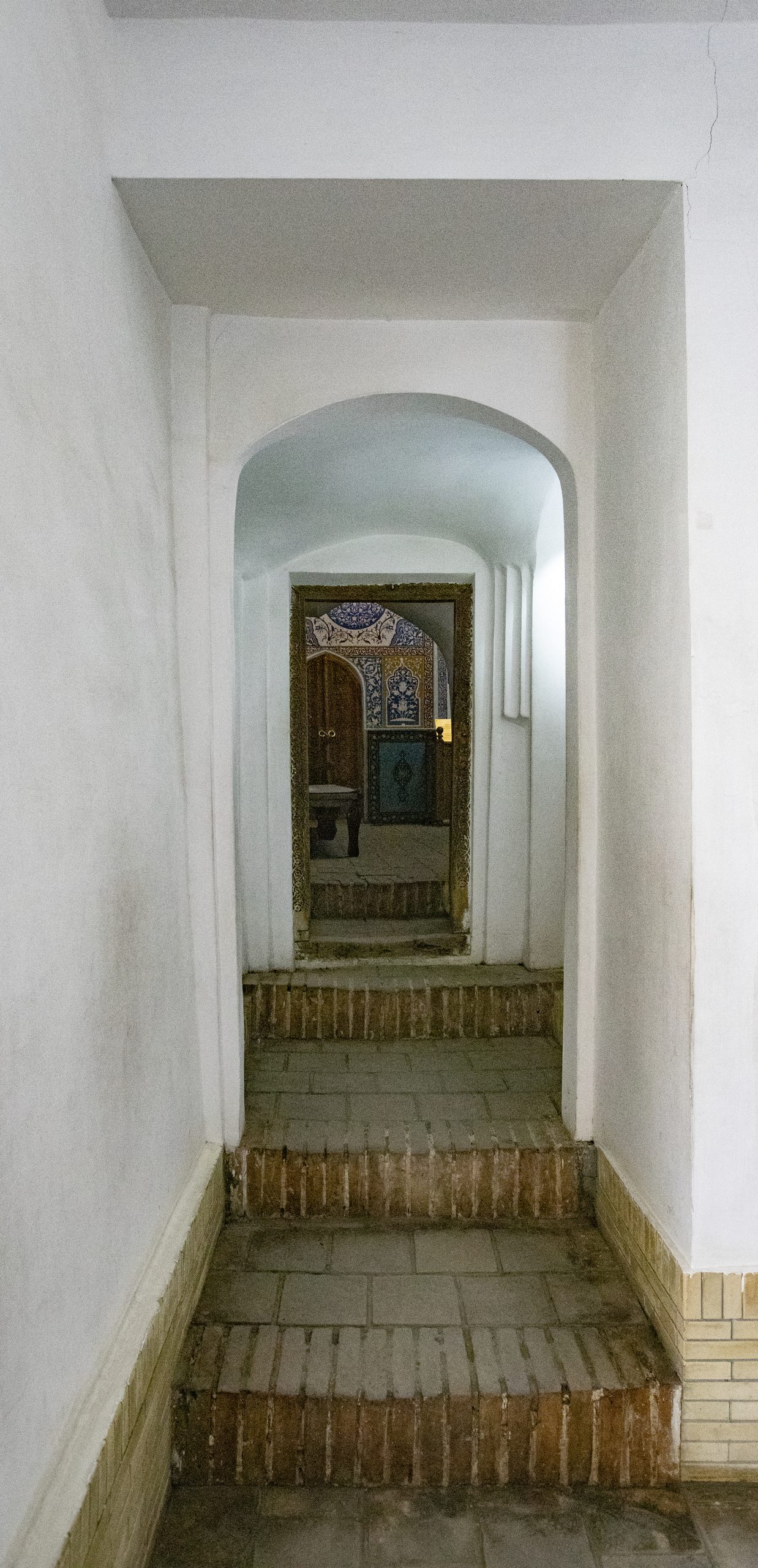 Passageway with stairs leading to a room with decorated walls.