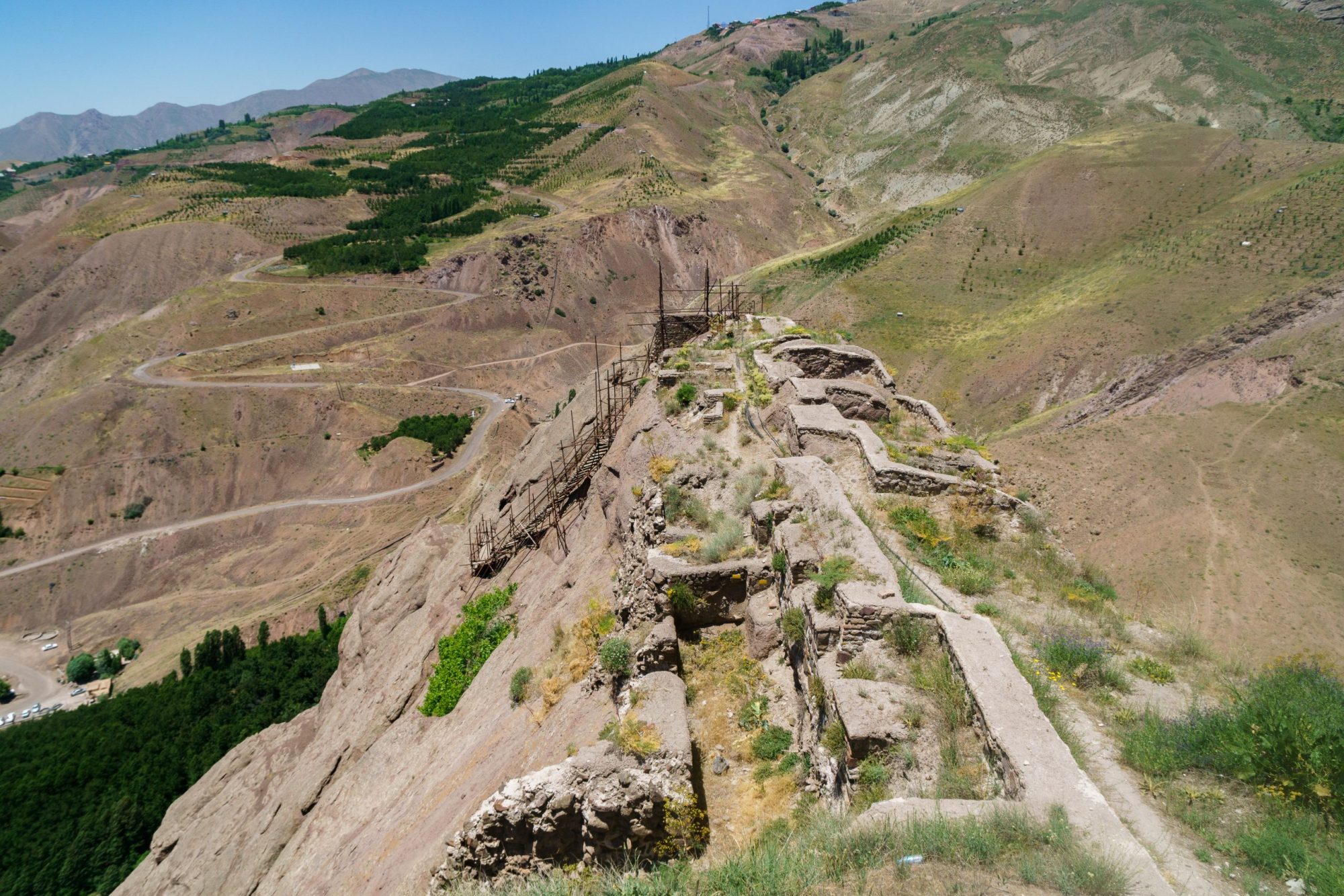 Ruins of a fort in a hilly area with different vegetation growing into the ruins.